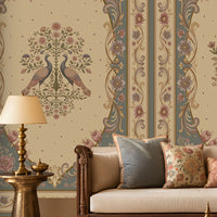 Vanamala Garden Mural Wallpaper - Slate Blue showcasing ornate peacock motifs, intricate floral medallions, and decorative heritage borders in dusky teal blue and ivory tones, styled in a luxurious traditional living room with carved wooden furniture, soft furnishings, and warm natural lighting.