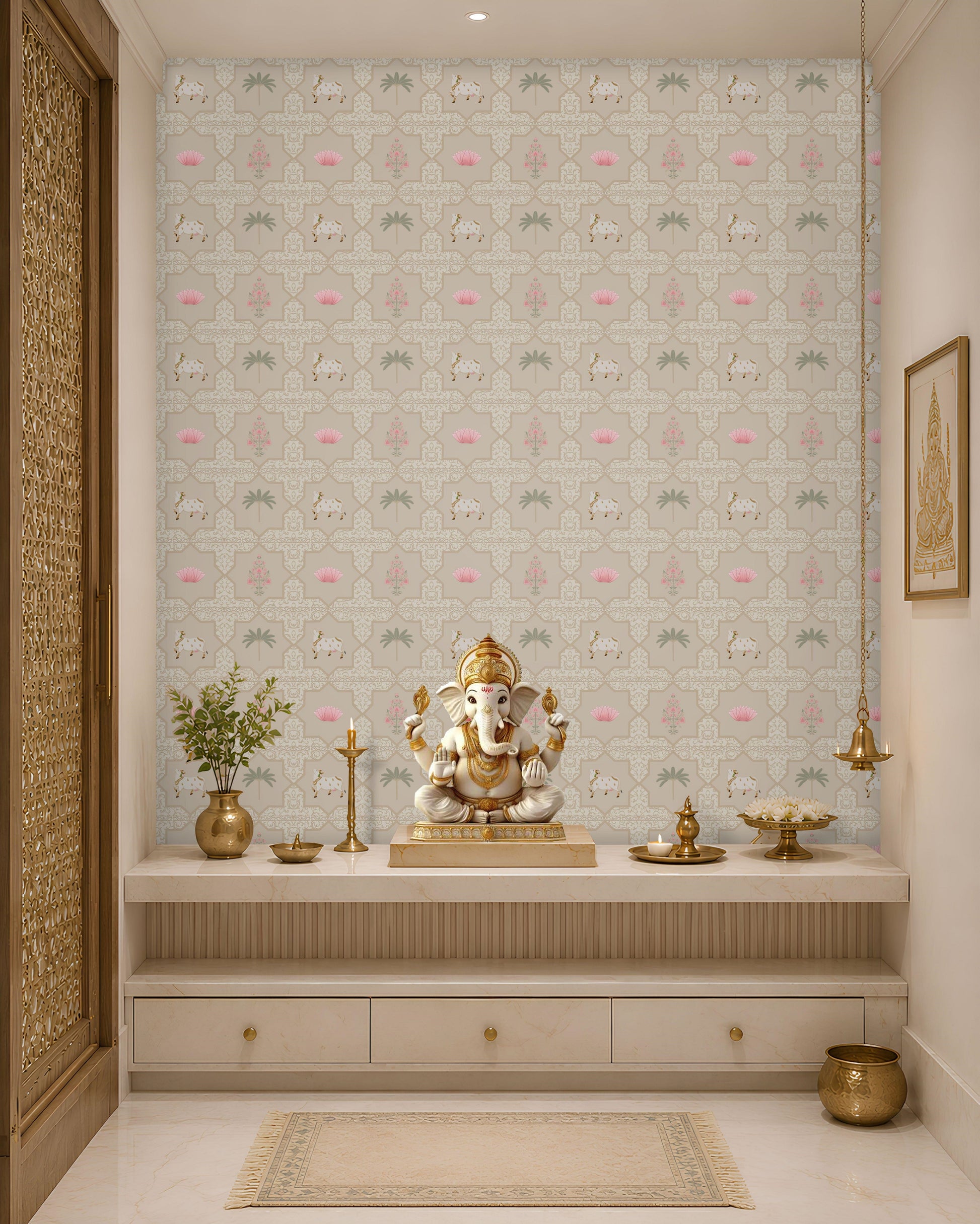 A serene Indian pooja room alcove or mandir backdrop featuring a beige Vraj Kamal Pichwai wallpaper patterned with cows and pink lotuses, styled with a Ganesha idol on a marble altar console and elegant brass fixtures.