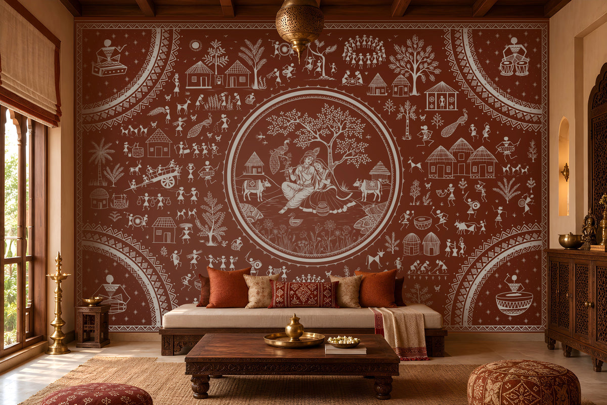 Warli Divine Harmony - Burnt Terracotta Red wallpaper featuring intricate white Warli tribal artwork with a central Radha Krishna motif, traditional village scenes, dancing figures, trees, huts, and decorative borders. Set in a warm Indian heritage-inspired living room with carved wooden furniture, earthy textiles, and elegant terracotta tones.