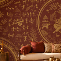 Warli Divine Harmony - Royal Maroon Traditional Warli art seamless wallpaper in burnt terracotta brown featuring intricate ivory tribal motifs, village scenes, huts, trees, peacocks, dancers, and a central Radha Krishna-inspired illustration, styled in an elegant Indian heritage living room with carved wooden furniture and warm earthy décor.