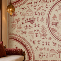 Warli Divine Harmony - Warm Ivory seamless wallpaper featuring intricate Warli tribal art with a central Radha Krishna motif, surrounded by village scenes, trees, huts, dancers, animals, and geometric borders in terracotta red on a warm ivory background. Displayed in a traditional Indian living room with carved wooden furniture and ethnic décor.