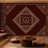 A large wall tapestry with an intricate geometric and tribal pattern in deep maroon and cream, displayed in a styled living room setting with a wooden coffee table, poufs, and a daybed.