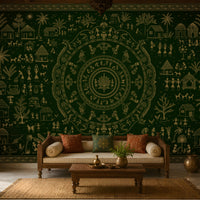 A large dark green wall tapestry with intricate beige folk art illustrations of houses, trees, and circular mandala motifs, displayed in a styled living room behind a wooden sofa.