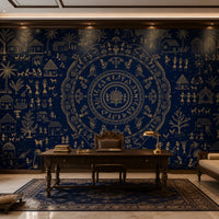 A large wall mural or wallpaper featuring an intricate navy blue and gold traditional circular mandala design with figures, houses, and trees, shown in a styled study with a wooden desk, chair, and sofa.