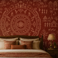 A styled bedroom featuring a large red and beige folk-art style wall mural behind a wooden bed. The room includes matching wood furniture, bedside tables with lamps, a bench at the foot of the bed, and potted plants near the window.