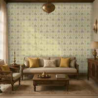 A warm, elegant living room with traditional wooden furniture and a soft floral-patterned wallpaper in muted yellow, sage green, and blush tones. A wooden sofa with beige upholstery and mustard accent cushions sits against the feature wall, complemented by a matching armchair, coffee table, sideboard, brass décor, and classic lighting. Large windows fill the space with natural light, creating a cozy and refined atmosphere.
