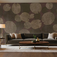 An architectural perspective of a modern luxury living room featuring the Whispers of the Pond Mural as a full-scale feature wall behind a large sectional sofa. The mural’s rhythmic, circular patterns create a sense of organic movement and tranquility, pairing perfectly with gold accents, dark wood furniture, and warm ambient lighting.