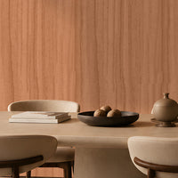 Wood Seamless Wallpaper - Cinnamon Peach showcased in a contemporary dining room featuring a warm almond beige wood-grain texture with a seamless vertical pattern. The wallpaper creates a sophisticated backdrop for neutral upholstered dining chairs, a round stone table, modern pendant lighting, and dark wood furniture, adding natural warmth, depth, and timeless elegance to the space.