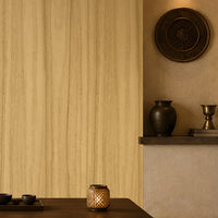 Wood Seamless Wallpaper - Golden Beige displayed in a serene Japandi-inspired living space. The wallpaper features a warm golden beige tone with delicate vertical wood grain textures, creating a seamless and natural backdrop. Paired with dark wood furniture, floor cushions, decorative pottery, ambient lighting, and earthy accents, the design brings warmth, texture, and timeless elegance to the interior.