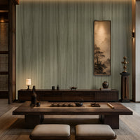 Wood Seamless Wallpaper - Moss Green displayed in a sophisticated Japandi-inspired living space. The wallpaper features a muted moss green tone with subtle vertical wood grain textures, creating a seamless natural look. Paired with dark wooden furniture, soft ambient lighting, neutral floor cushions, and elegant décor accents, the wallpaper adds depth, warmth, and a calming organic aesthetic to the interior.