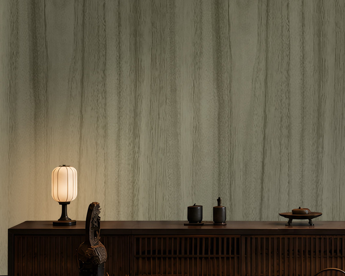 Wood Seamless Wallpaper - Moss Green displayed in a sophisticated Japandi-inspired living space. The wallpaper features a muted moss green tone with subtle vertical wood grain textures, creating a seamless natural look. Paired with dark wooden furniture, soft ambient lighting, neutral floor cushions, and elegant décor accents, the wallpaper adds depth, warmth, and a calming organic aesthetic to the interior.