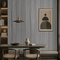 Wood Seamless Wallpaper - Textured Ash Grey featured in a modern dining space. The wallpaper showcases a sophisticated ash grey tone with seamless vertical wood grain textures, creating a refined and contemporary backdrop. Paired with dark wood furniture, warm ambient lighting, built-in shelving, and minimalist décor, the design adds depth, texture, and understated elegance to the interior while maintaining a calm and modern aesthetic.