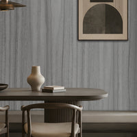 Wood Seamless Wallpaper - Textured Ash Grey featured in a modern dining space. The wallpaper showcases a sophisticated ash grey tone with seamless vertical wood grain textures, creating a refined and contemporary backdrop. Paired with dark wood furniture, warm ambient lighting, built-in shelving, and minimalist décor, the design adds depth, texture, and understated elegance to the interior while maintaining a calm and modern aesthetic.