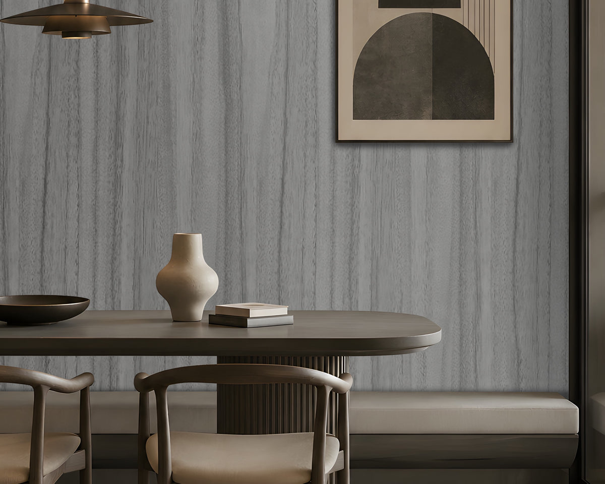Wood Seamless Wallpaper - Textured Ash Grey featured in a modern dining space. The wallpaper showcases a sophisticated ash grey tone with seamless vertical wood grain textures, creating a refined and contemporary backdrop. Paired with dark wood furniture, warm ambient lighting, built-in shelving, and minimalist décor, the design adds depth, texture, and understated elegance to the interior while maintaining a calm and modern aesthetic.
