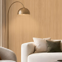 Warm Sand Wood Seamless Wallpaper featuring a subtle natural wood grain texture in soft beige and warm sandy tones, creating a calm, elegant, and sophisticated interior wall finish. The seamless vertical wood pattern adds gentle depth and a natural organic feel while maintaining a clean and refined appearance. The wallpaper is showcased across a spacious feature wall in a bright contemporary living room with neutral cream furniture, a dark round coffee table, textured rug, earthy brown cushion