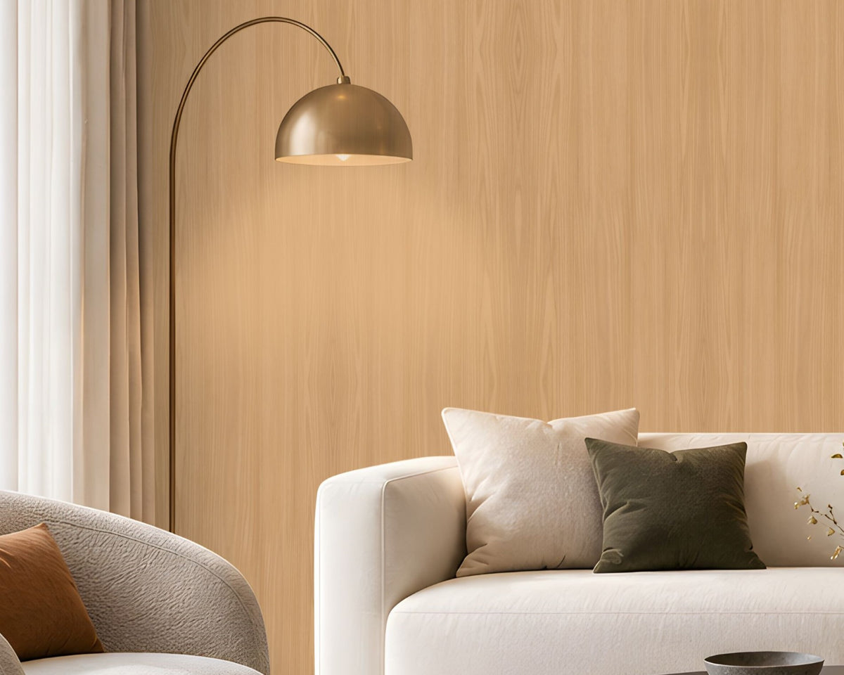 Warm Sand Wood Seamless Wallpaper featuring a subtle natural wood grain texture in soft beige and warm sandy tones, creating a calm, elegant, and sophisticated interior wall finish. The seamless vertical wood pattern adds gentle depth and a natural organic feel while maintaining a clean and refined appearance. The wallpaper is showcased across a spacious feature wall in a bright contemporary living room with neutral cream furniture, a dark round coffee table, textured rug, earthy brown cushion